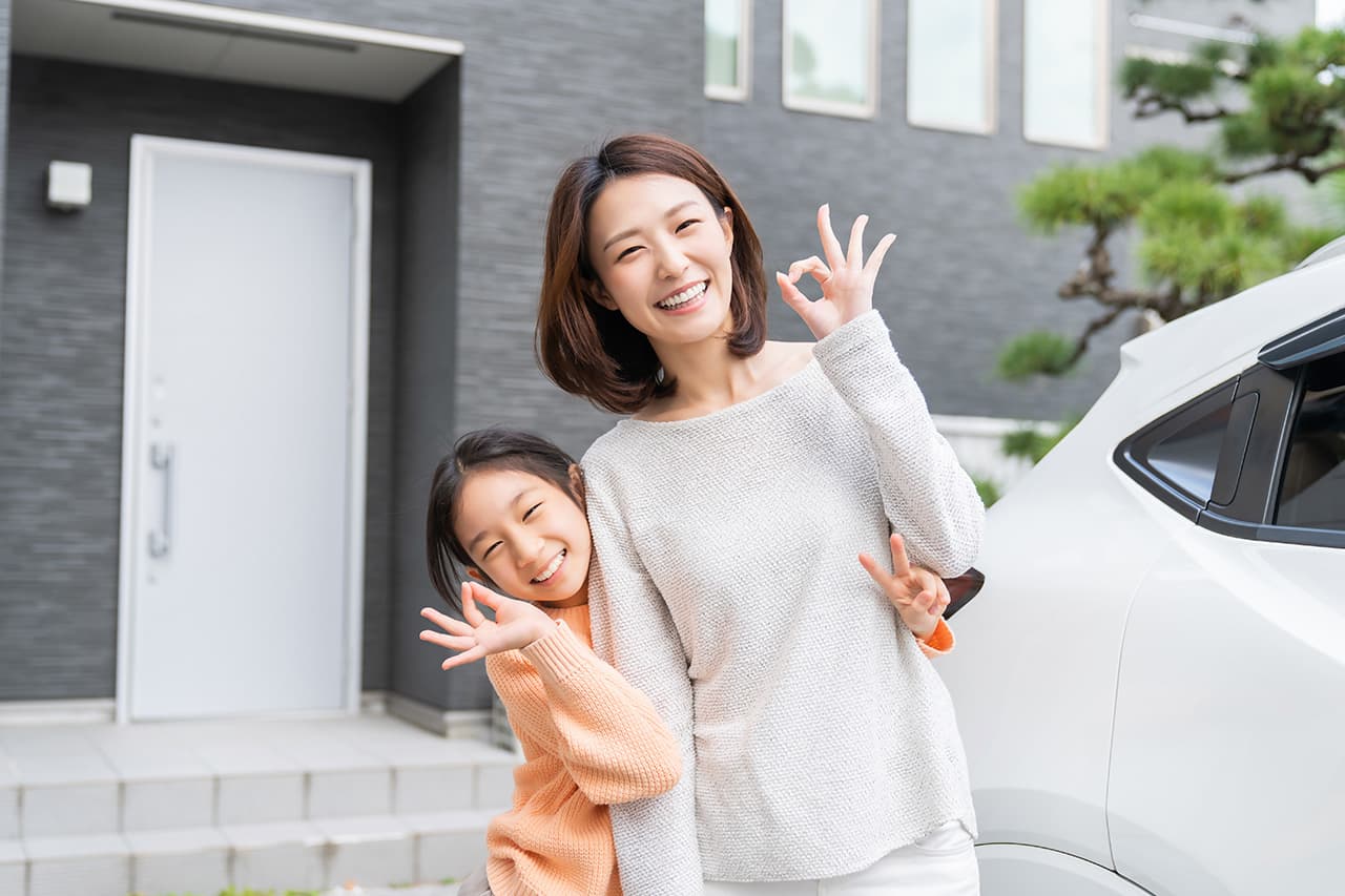 玄関の前の車の横で笑顔の親子